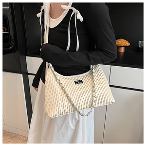 Detail of cream pleated shoulder bag with silver chain and metal twist lock on the front