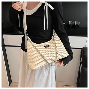 Detail of cream pleated underarm bag with silver chain strap and metal twist lock