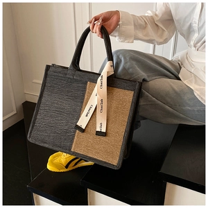 Detail of contrast stitch tote bag featuring grey tweed fabric and woven brand strap
