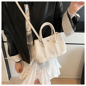 Detail of vertical pleated texture on cream-colored bucket bag with dual handles