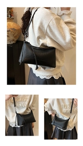Detail of black pleated PU leather hobo bag showing adjustable strap and vertical texture