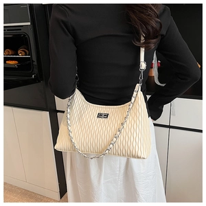 Close-up of the beige pleated texture and silver chain strap on this elegant handbag