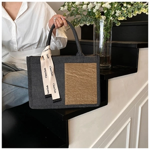 Detail of grey canvas tote with brown pocket and decorative printed ribbon handle