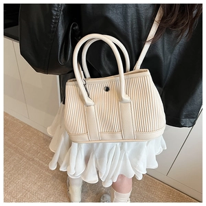 Detail of cream pleated bucket bag with metal buckle and adjustable shoulder strap