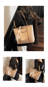 Detail view of large beige tote bag with brown straps and floral scarf on stairs
