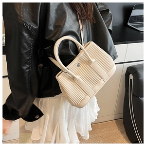 Close-up of cream pleated leather bucket bag featuring a decorative silver buckle