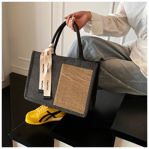 Detail of grey textured canvas tote bag with contrast gold panel and printed ribbon strap