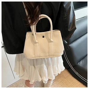 Detailed back view of a beige pleated bucket bag on a model wearing a leather jacket
