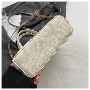 Gros plan détaillé du fond de sac en cuir beige avec bandoulière marron réglable