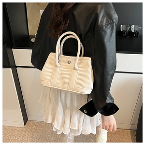 Close-up of cream pleated leather bucket bag with silver metal ring and round handles