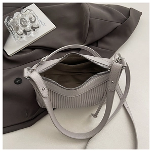 Close-up of internal zip pocket and textured pleat material on grey underarm bag