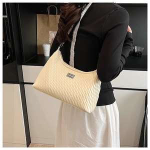 Close-up of cream pleated shoulder bag featuring a silver rectangular twist lock closure
