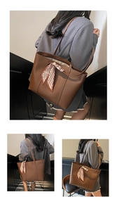 Detailed view of a brown faux leather tote bag with a chic plaid silk scarf detail