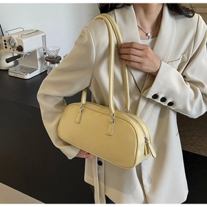 Detail of a light yellow ballet-style bow handbag shown worn as an underarm pillow bag