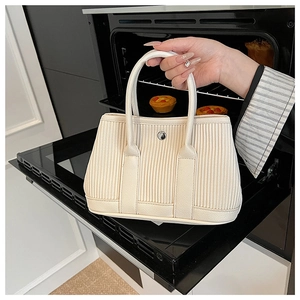 Detail of beige pleated bucket bag texture with metallic stud decoration on the side