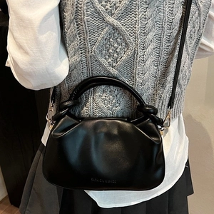 Minimalist black pleated bucket bag with knot handle for a modern crossbody street look