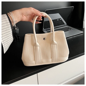 Detailed close-up of cream pleated bucket bag texture with silver metal buckle