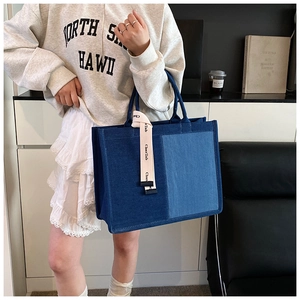Close-up of contrast denim patchwork tote bag with stylish cream lettered strap detail