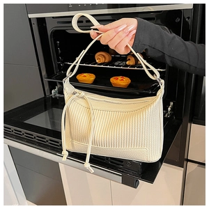Détail de la texture en cuir plissé crème sur un sac hobo en forme de croissant