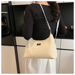 Detail of beige pleated shoulder bag featuring a silver metal chain and textured wavy design
