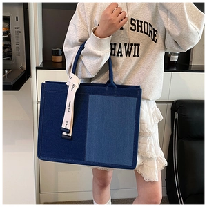 Detail of blue patchwork denim tote bag with white branded ribbon and large capacity