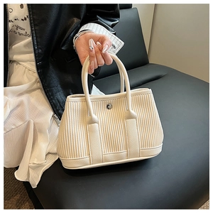 Detail of cream white bucket bag featuring vertical pleated texture and silver metal buckle
