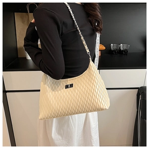 Detail of cream hobo bag featuring vertical wave pleats and a metal chain strap