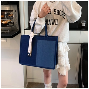Detail of a patchwork blue denim tote bag with decorative Chan'2ab ribbon handle strap