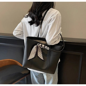 Detail of a large black tote bag with a decorative geometric silk scarf on the handle