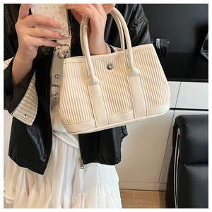 Detail of off-white corduroy tote bag featuring vertical texture and silver snap button
