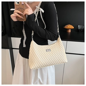 Close-up of cream pleated shoulder bag with silver chain strap and metal lock detail