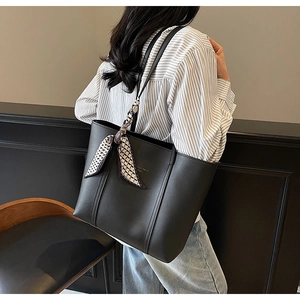 Detail of black leather tote bag with Fashion Trend print and geometric silk scarf
