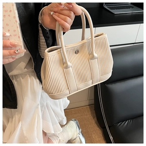 Close-up of pleated texture on a cream bucket bag with round metal detail