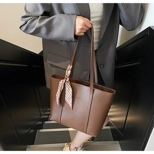 Detail of brown tote bag with check scarf handle on model in minimalist stairs