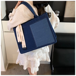 Chic patchwork denim tote bag in dark and light blue with a stylish branded ribbon strap