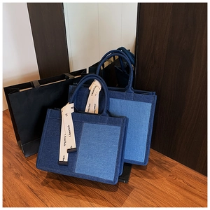 Detailed macro view of dual-tone denim patchwork tote bag with stylish ribbon handles