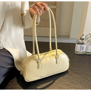 Detailed view of pale yellow pleated leather texture on a trendy bow handle handbag