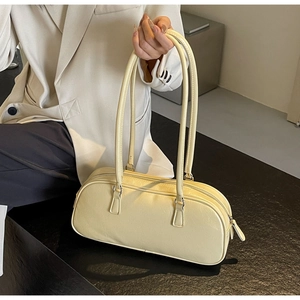 Close-up of minimalist butter yellow leather shoulder bag with sleek silver hardware detail