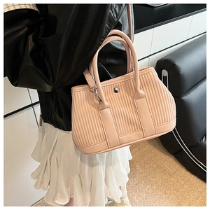 Detail of pleated pink-orange bucket bag showing textured PU leather and metal hardware