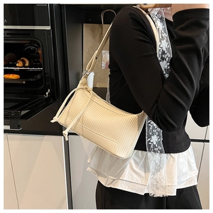 Minimalist beige baguette bag with square quilted texture and decorative side drawstrings
