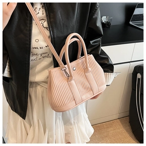 Detail of light pink pleated bucket bag featuring lychee grain leather and silver buckles
