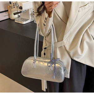 Silver metallic shoulder bag with checkered bow detail worn on model shoulder