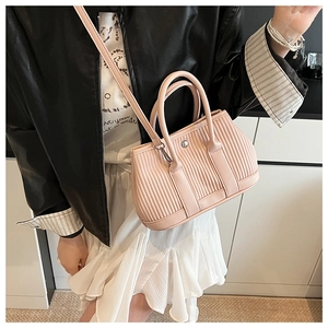 Detail of pink pleated bucket bag with silver buckle worn by a model in casual outfit