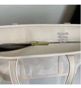 Detail of smooth gold zipper and reinforced stitching on cream tote bag