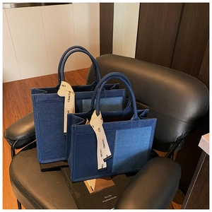 Detailed view of two navy denim tote bags with side patchwork and printed ribbon décor
