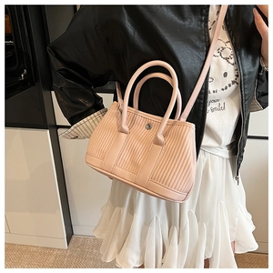Light pink pleated bucket bag worn with casual outfit showing shoulder strap and texture