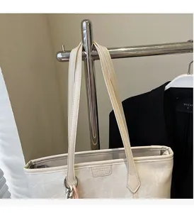 Detail of cream tote bag with thin shoulder straps and embossed fashion logo patch