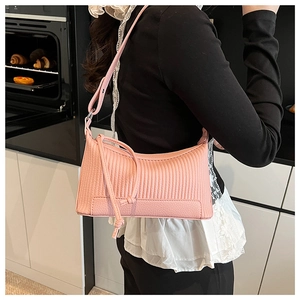 Detail of pink pleated underarm bag with decorative rope knots worn on shoulder