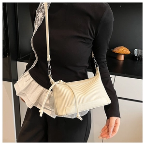 Detail view of the vertical pleated texture and leather corner reinforcement on the cream bag