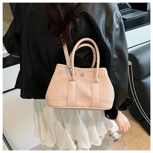 Detail of pink pleated bucket bag with silver clasp shown worn by a model in a casual setting